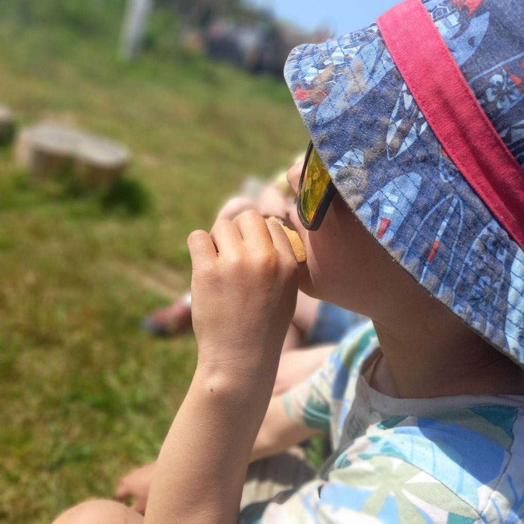 A young child in a sun hat exploring outdoors at the centre