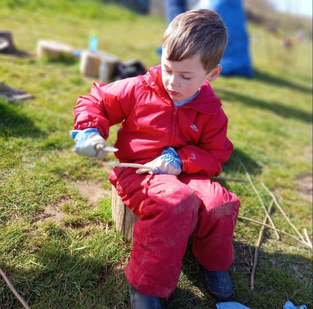 A child playing with metal bowls on the grass